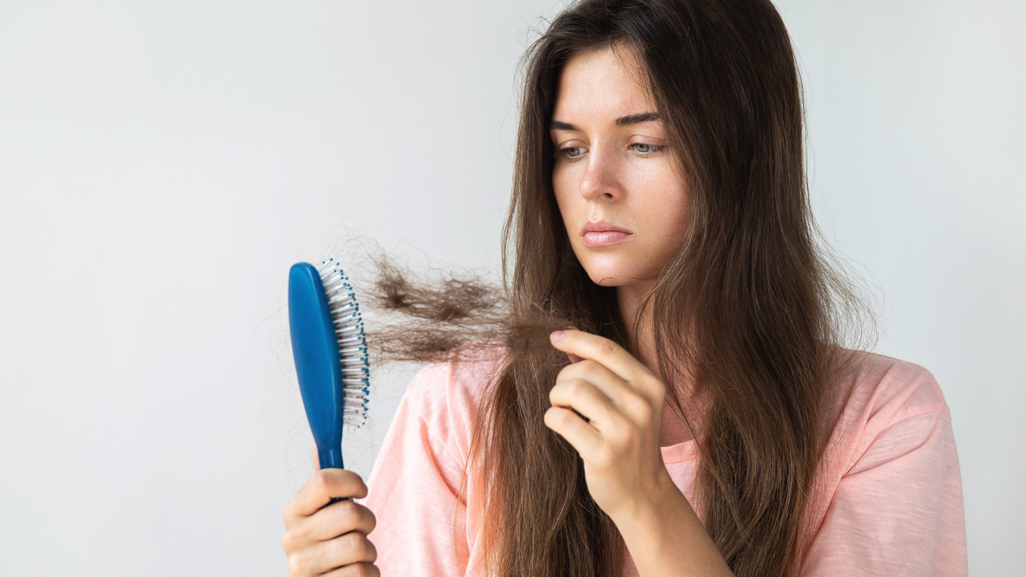 Postpartum hair loss – woman removing loose hair from hairbrush