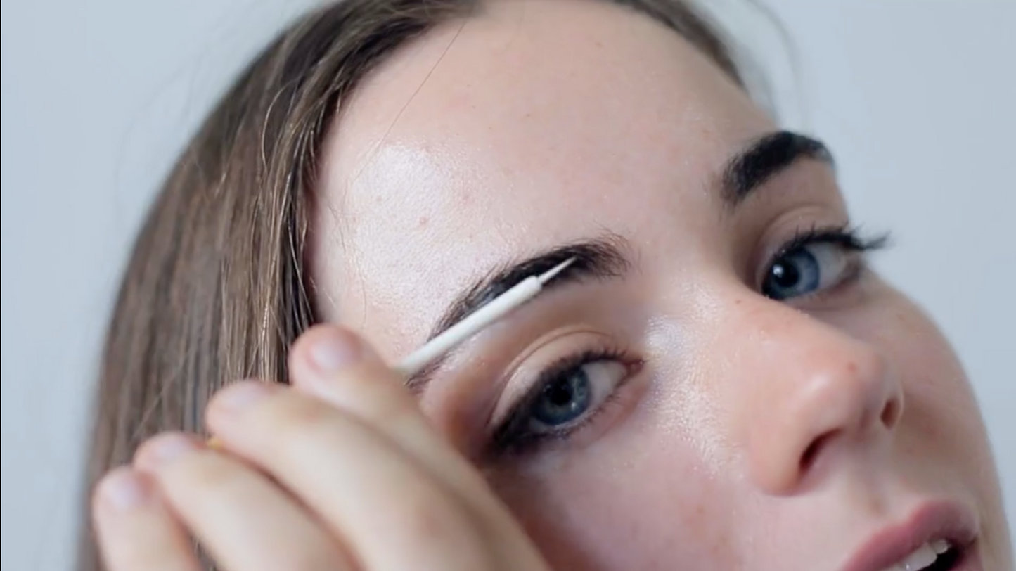 woman applying lash and brow serum along brows to support natural lash and brow care